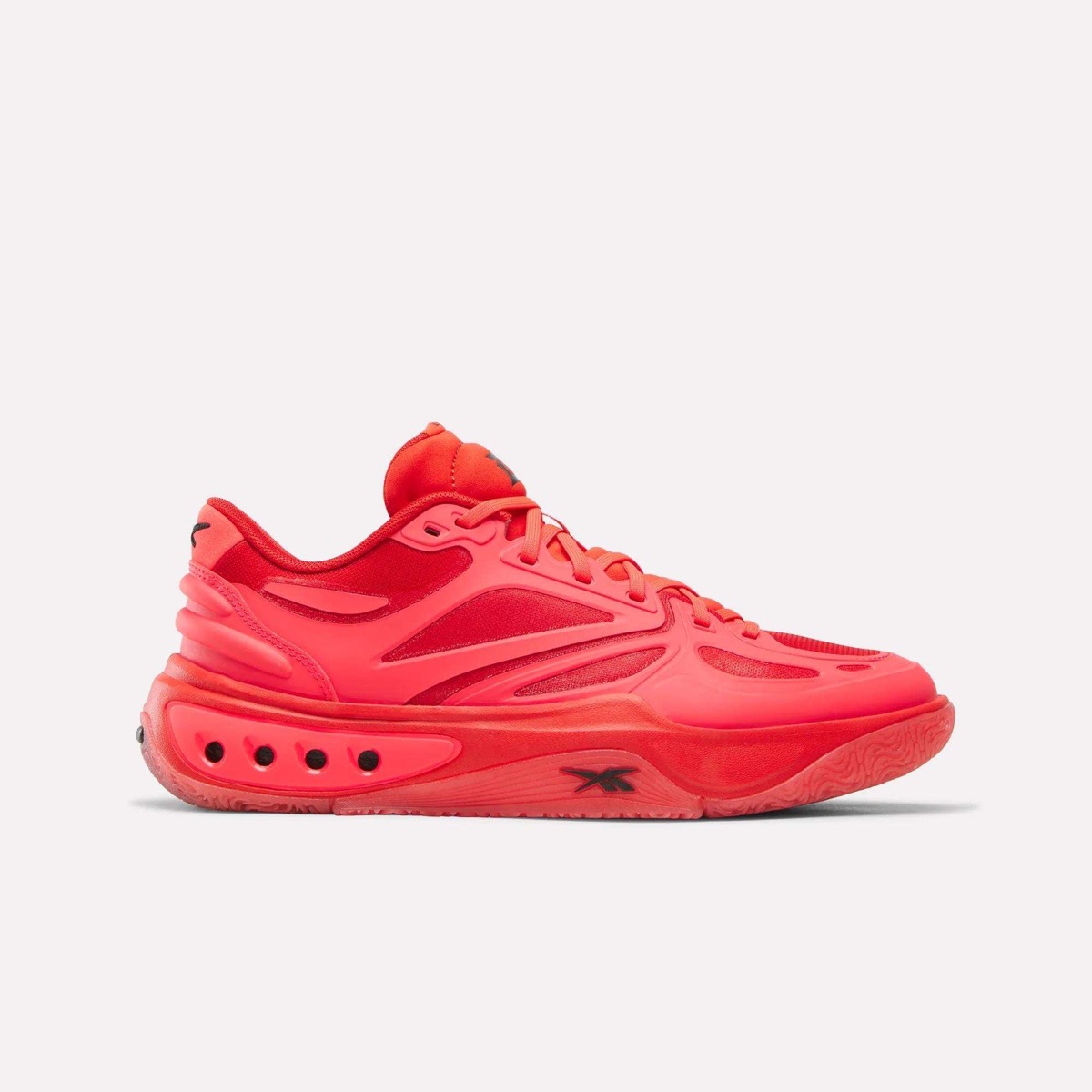 Reebok Engine A de Darius Acuff Jr. de perfil sobre fondo blanco, toda roja con la capellada moldeada, el vector de Reebok en negro y los huecos en la suela