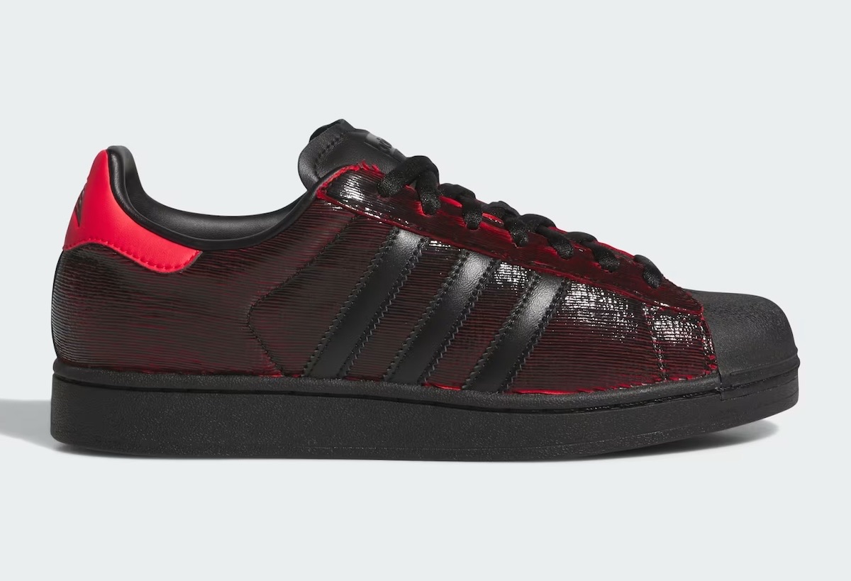 adidas Superstar Halloween de Anthony Edwards de perfil sobre fondo gris claro, con capellada negra y rayada que deja ver el rojo, talón rojo y suela negra