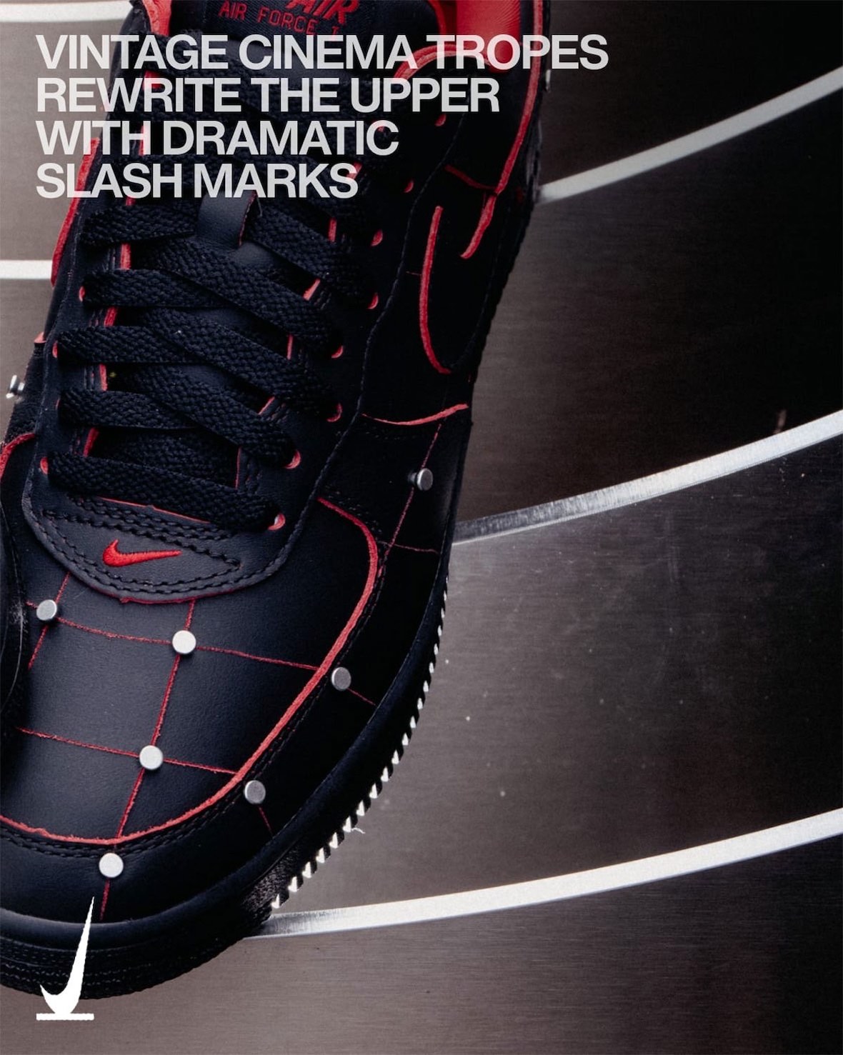 Vista lateral cercana del Nike Air Force 1 '01 Nightmare, con el cuero negro marcado por líneas rojas, tachas plateadas, el swoosh rojo en la puntera y el logo Air rojo en la lengüeta, con texto de campaña en inglés arriba