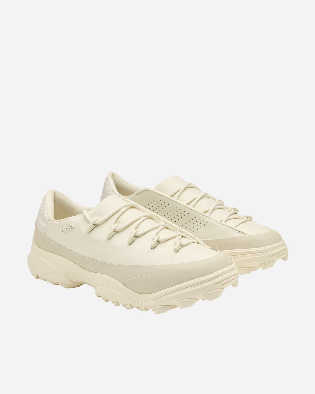 Par de la Arte Antwerp x adidas GSG9 Off White en vista de tres cuartos sobre fondo blanco, con el upper crudo, la palabra arte en relieve en un lateral, perforaciones en el lateral interno del otro pie, cordones redondos con pasadores y la suela de tacos marcados