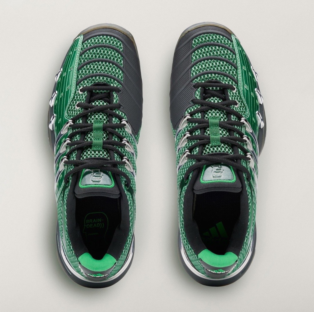 Vista desde arriba del par del Brain Dead x adidas Barricade V Dark Green sobre fondo gris claro, con malla verde, paneles laterales gris oscuro, cordones negros, la lengüeta verde con logo, el logo de Brain Dead en la plantilla izquierda y el de adidas en la derecha