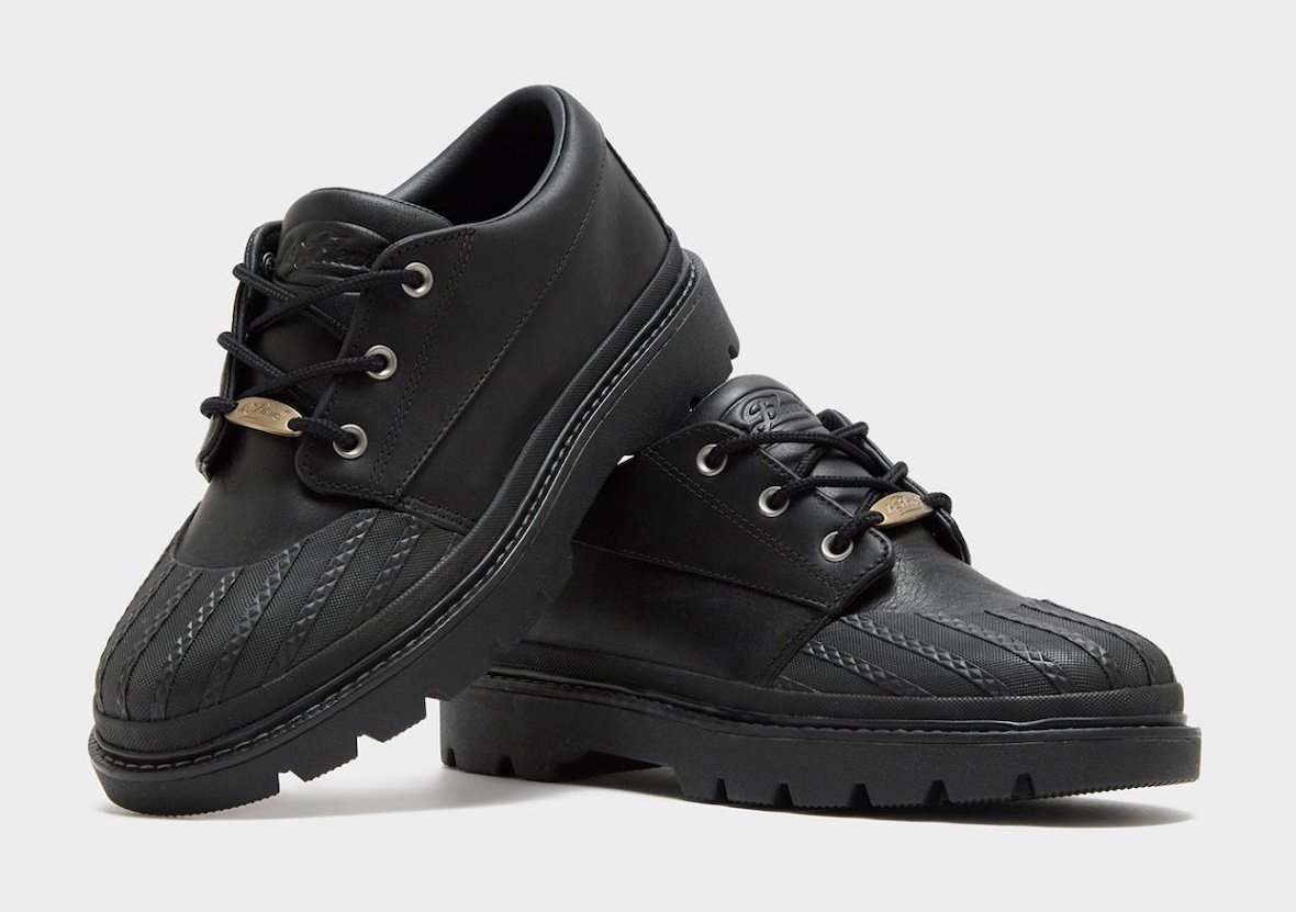 Par del Converse 1908 Bronco Boot Low negro, todo en cuero negro con puntera de goma texturada, ojales plateados, plaqueta dorada en los cordones y suela dentada negra
