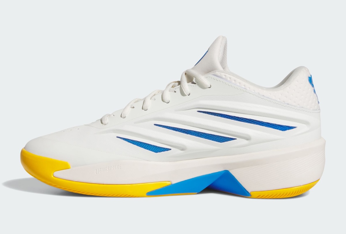 Perfil lateral de la adidas Crazy Energy Wagner Brothers sobre fondo gris claro, con upper blanco hueso, tres tiras azules, suela amarilla y un detalle azul en la mediasuela con la palabra Lightstrike