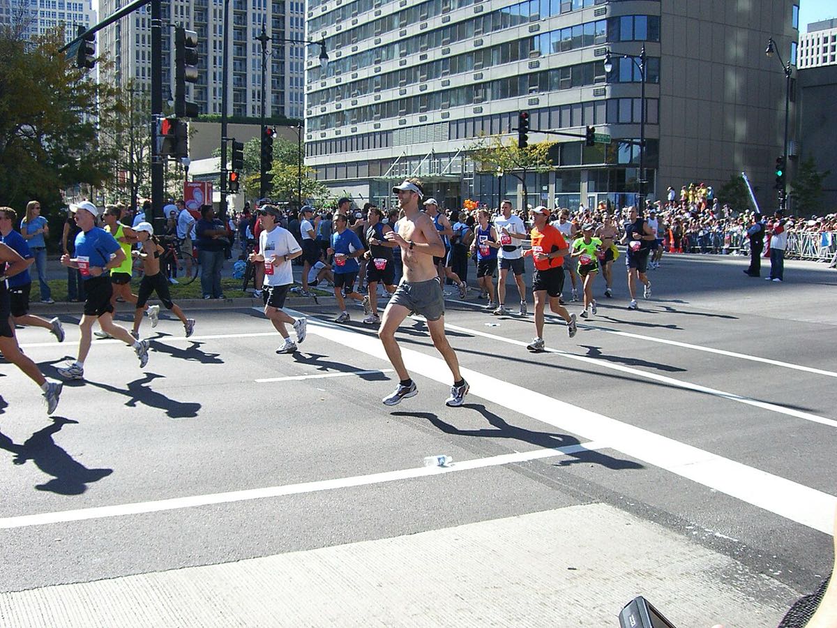 Corredores con remeras de colores avanzan por una avenida del centro de Chicago, entre edificios y público detrás de las vallas, durante el maratón de 2008