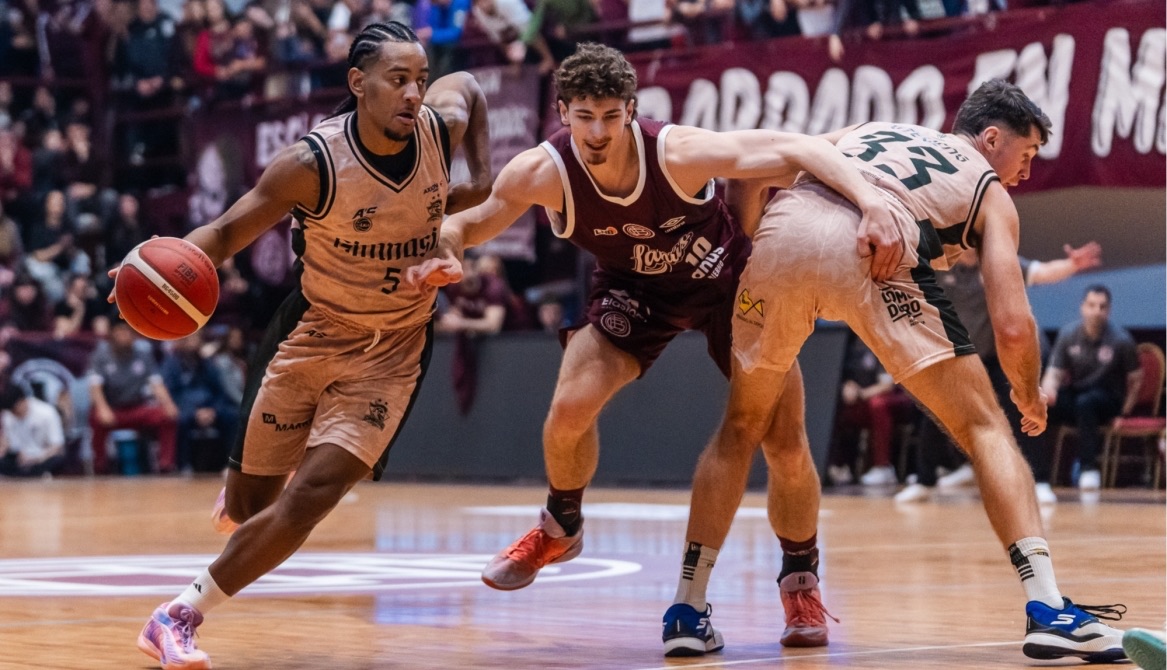 Un jugador de Gimnasia de Comodoro avanza con la pelota ante la marca de dos jugadores de Lanús en el partido inaugural de la Liga Nacional