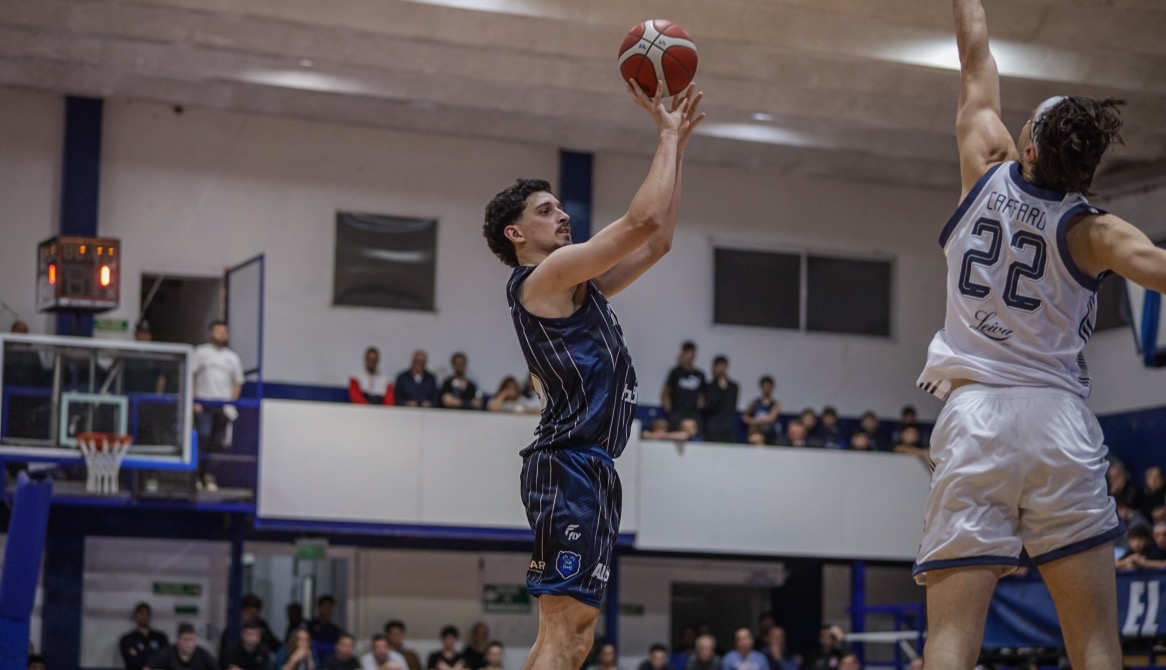 Un jugador de Argentino, con camiseta azul oscura a rayas, lanza ante la marca de un rival de camiseta blanca