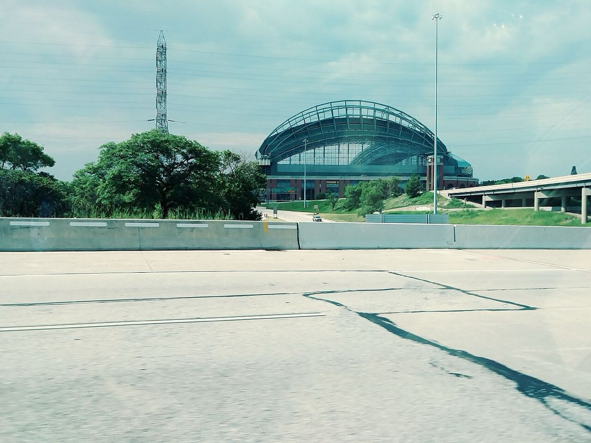 Imagen del estadio: el American Family Field visto desde la autopista, con su techo de arcos y un cielo nublado