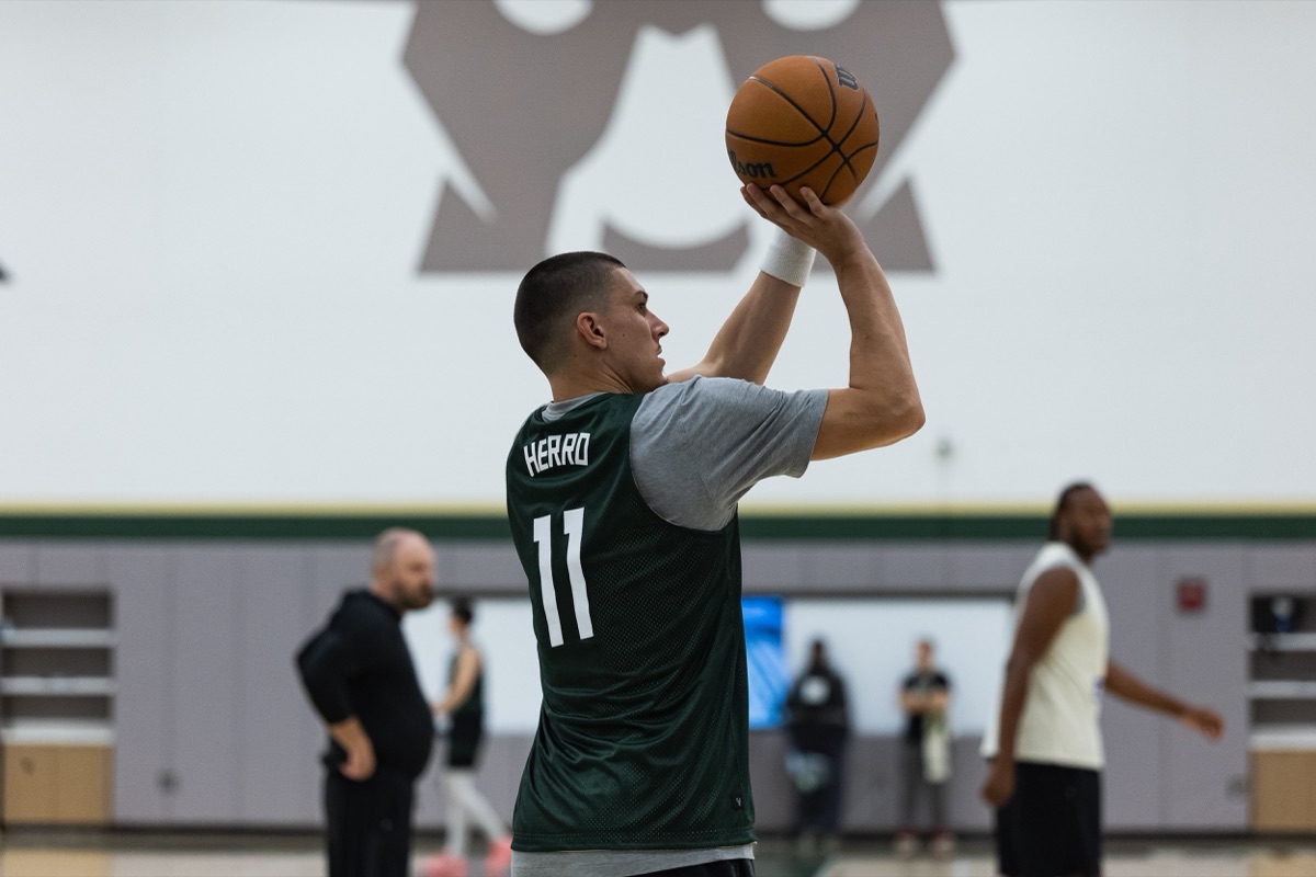 Tyler Herro, con la musculosa verde número 11 de los Bucks, lanza en la práctica del día del partido en Milwaukee