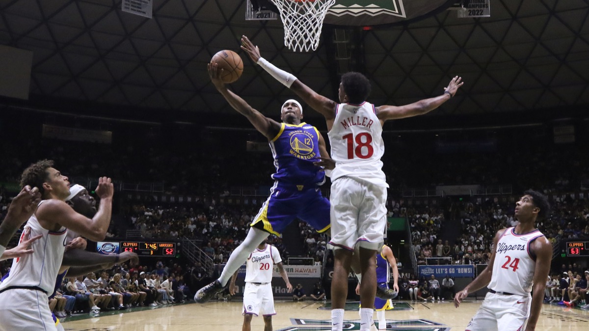 Brandon Williams, con la camiseta azul número 12 de Golden State, va hacia el aro ante la marca de Baba Miller, de los Clippers, en el Stan Sheriff Center de Honolulu