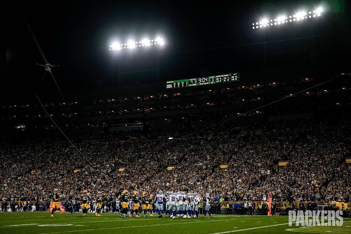 Lambeau Field de noche, con las luces del estadio encendidas sobre la tribuna llena y los jugadores de los Packers y los Cowboys en el campo durante el Sunday Night Football