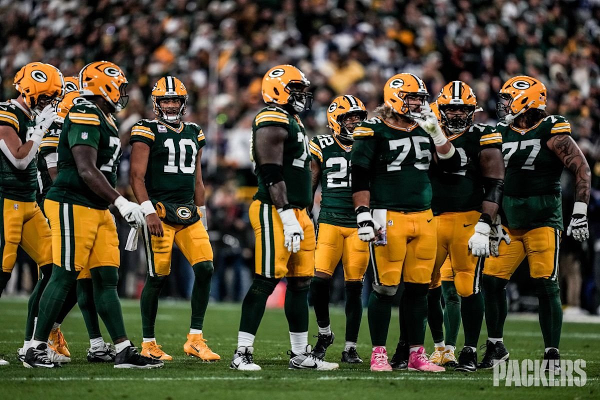 Jordan Love, con la camiseta verde número 10 de los Packers, en el medio del grupo de la línea ofensiva antes de una jugada en Lambeau Field