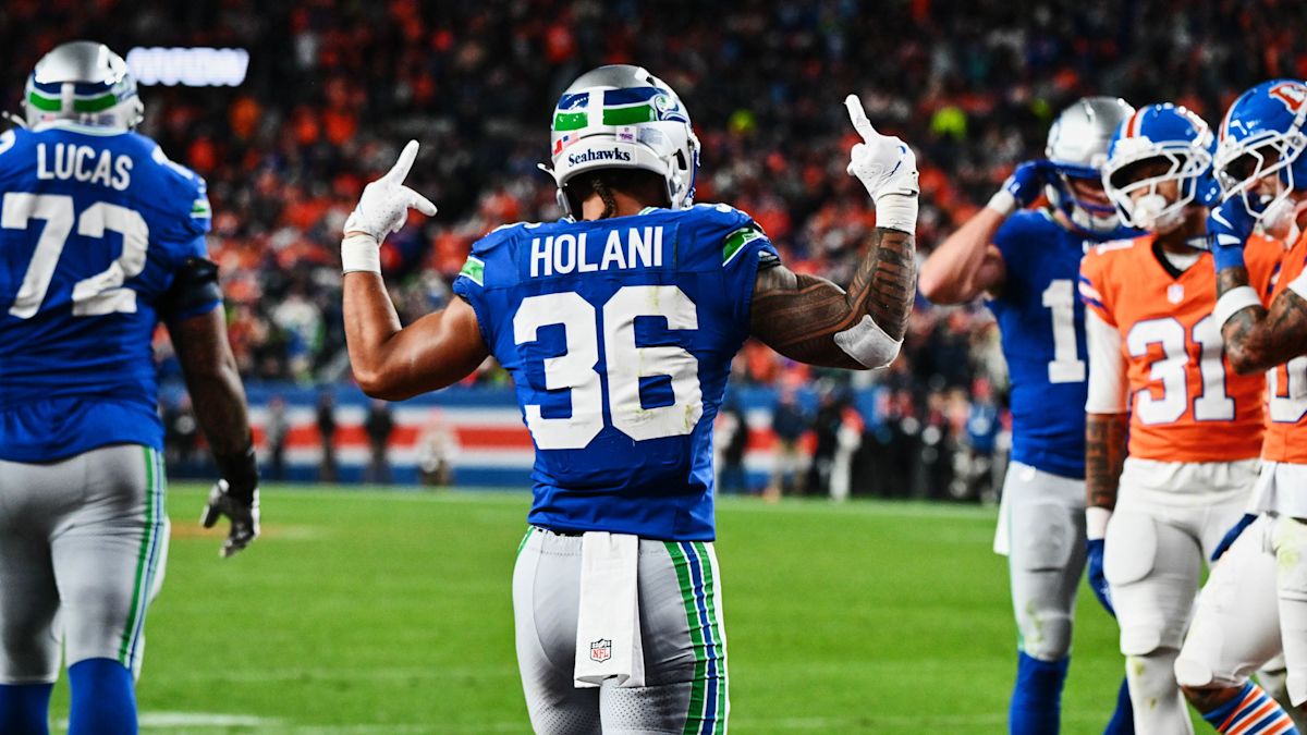 George Holani, con la camiseta azul número 36 de los Seahawks, festeja de espaldas con los dos dedos índice en alto, rodeado de compañeros y de jugadores de los Broncos