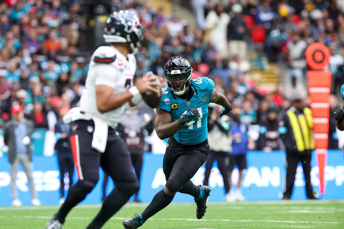 Un defensor de los Jaguars con la camiseta turquesa número 41 y la C de capitán corre hacia el quarterback de los Texans, de camiseta blanca, que prepara un pase en Wembley