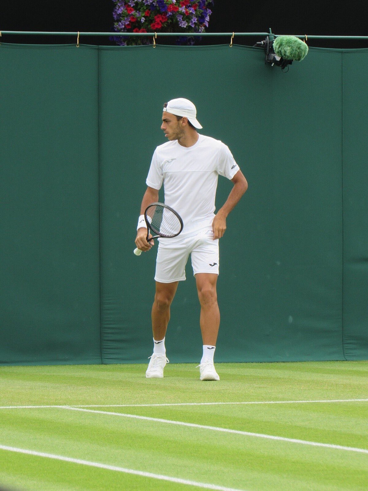Foto de archivo: Francisco Cerúndolo, de blanco, mira hacia un costado con la raqueta en la mano en una cancha de césped de Wimbledon
