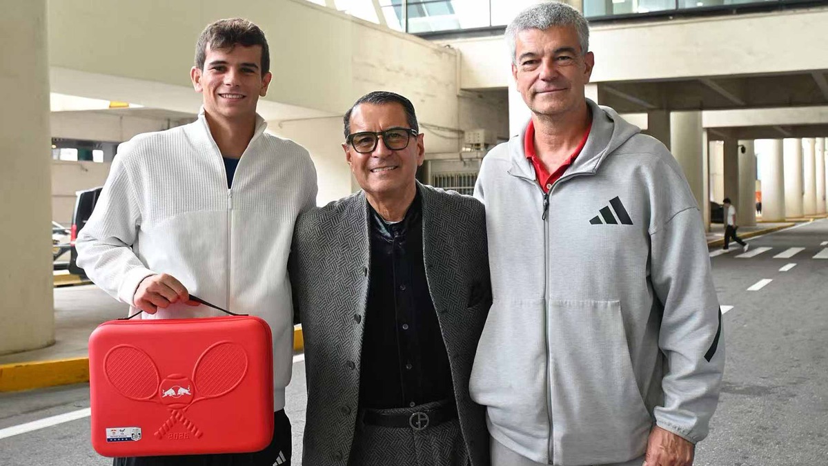 Rafael Jodar, con campera blanca, sostiene un maletín rojo de regalo junto a dos hombres, uno de saco gris y otro de buzo gris, en la salida de un aeropuerto de Shanghái