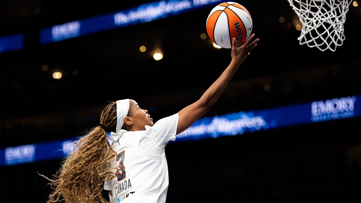 Jordin Canada, con la camiseta blanca del Atlanta Dream, salta para dejar una bandeja en el aro durante un partido