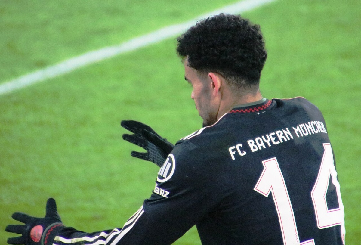 Luis Díaz de espaldas, con la camiseta negra número 14 del FC Bayern München, se acomoda los guantes sobre el césped; foto de archivo de enero de 2026 (foto: Werner100359, Wikimedia Commons, licencia CC BY-SA 4.0)