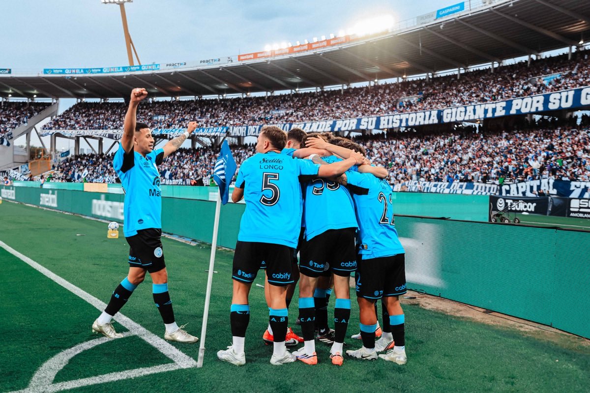 Jugadores de Belgrano se abrazan junto al banderín del córner, con las tribunas del Kempes de fondo, durante el clásico ante Talleres (foto: prensa Club Atlético Belgrano)