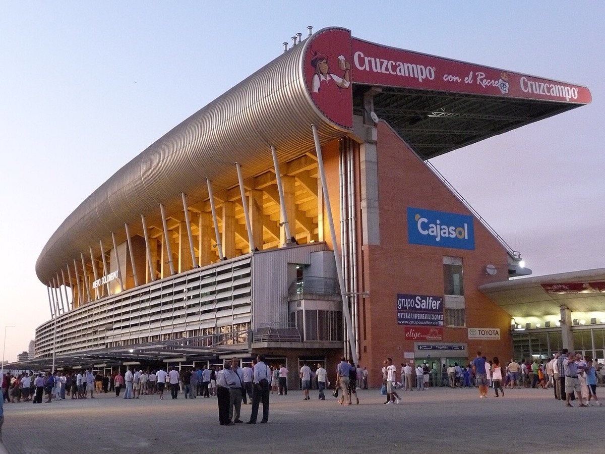 El estadio Nuevo Colombino, casa del Recreativo de Huelva, con su tribuna principal de techo curvo al atardecer y público en la explanada de acceso (foto de archivo: Calapito, Wikimedia Commons, CC BY 3.0)