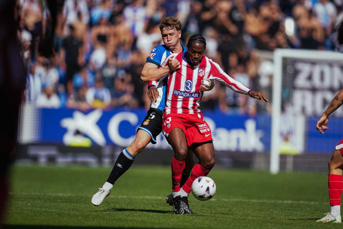 Un jugador del Atlético de Madrid, de rojo y blanco, aguanta la pelota ante la marca de un defensor del Espanyol en el RCDE Stadium (foto: prensa RCD Espanyol)