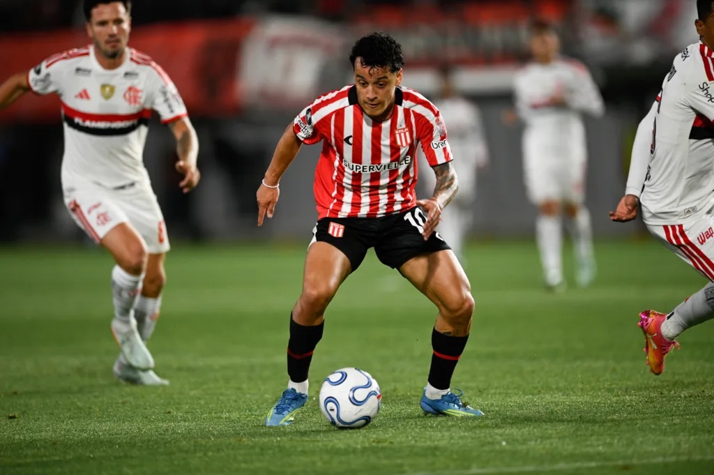 Un jugador de Estudiantes con la camiseta albirroja y el número 10 conduce la pelota mientras lo rodean futbolistas de Flamengo de blanco, en el estadio UNO de La Plata (foto: prensa oficial de Estudiantes de La Plata)