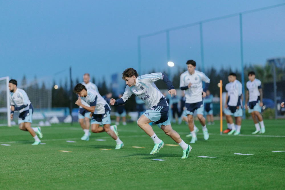 Jugadores de la Selección Argentina hacen piques de velocidad en el césped del predio de Ezeiza durante un entrenamiento al atardecer (foto oficial de la AFA)