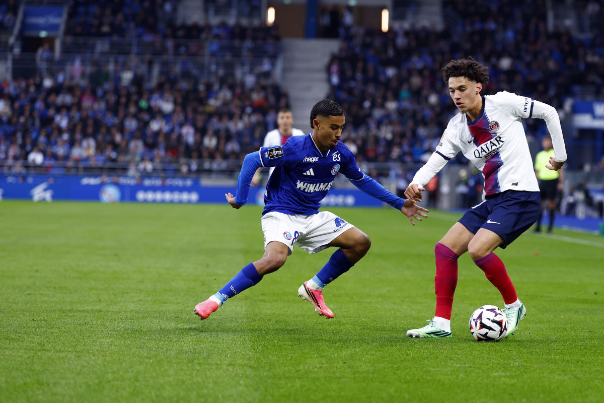 Un jugador del Strasbourg, con camiseta azul y pantalón blanco, intenta cortar a un jugador del PSG, de camiseta blanca, que conduce la pelota en La Meinau (foto: prensa Paris Saint-Germain)