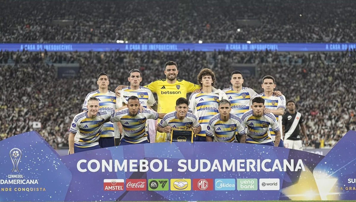 El equipo titular de Boca, con la camiseta blanca de franjas azules y amarillas y el arquero de amarillo, posa detrás del cartel de la CONMEBOL Sudamericana antes del partido, con el Maracaná lleno de fondo (foto: prensa Boca Juniors)