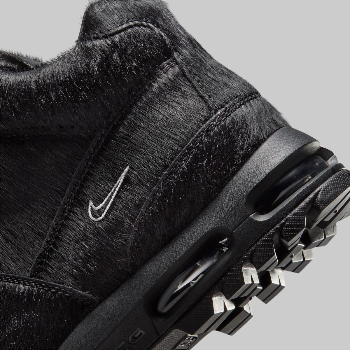 Detalle del lateral de la Nike Air Max Goadome Black Pony Hair, con el pelo negro, el Swoosh blanco bordado y la cámara de aire en la entresuela