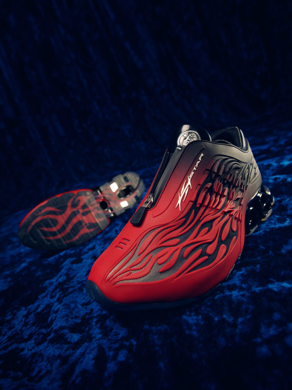 Campaña del HELLSTAR x adidas Megaride S2 Red/Black: el par en primer plano sobre terciopelo azul oscuro, con el cierre, el logo de HELLSTAR en el lateral y las llamas en relieve, y detrás la suela translúcida con llamas rojas