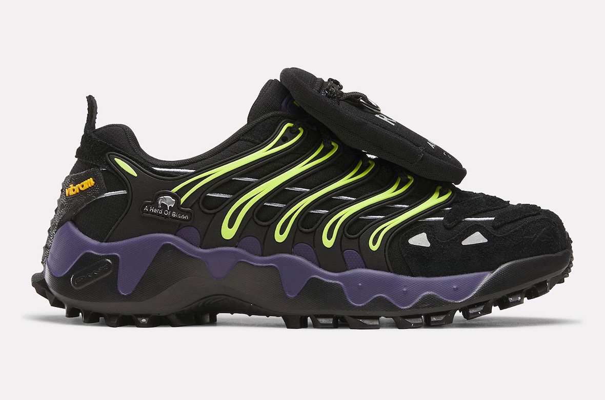 Reebok DMX Trailzillo de A Herd of Bison de perfil sobre fondo gris claro, negra con líneas verde lima, logo Vibram naranja en el costado y entresuela violeta con forma ondulada