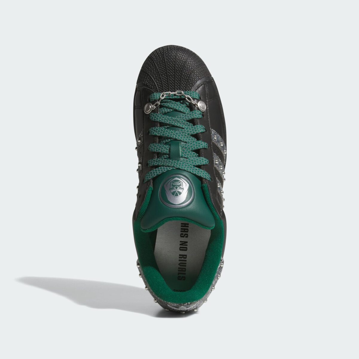 Vista desde arriba del adidas Superstar Doctor Doom con cordones verdes, la máscara plateada en la lengüeta y la frase Has No Rivals en la plantilla