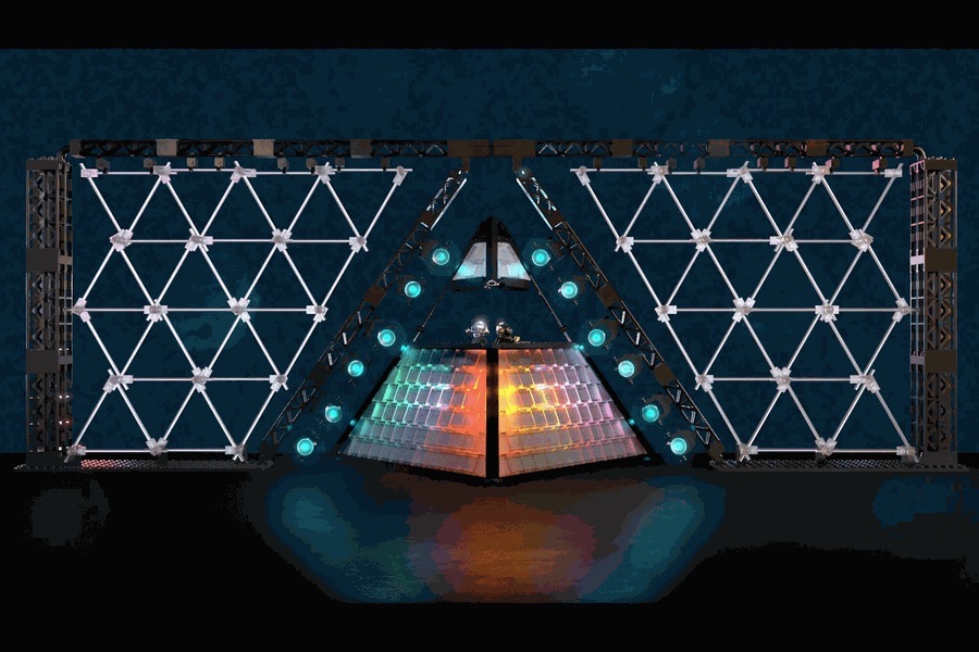 El diseño original de la pirámide de Daft Punk presentado en LEGO Ideas: el escenario con forma de triángulo, con paneles de luces y una estructura de triángulos a los costados, iluminado sobre fondo oscuro