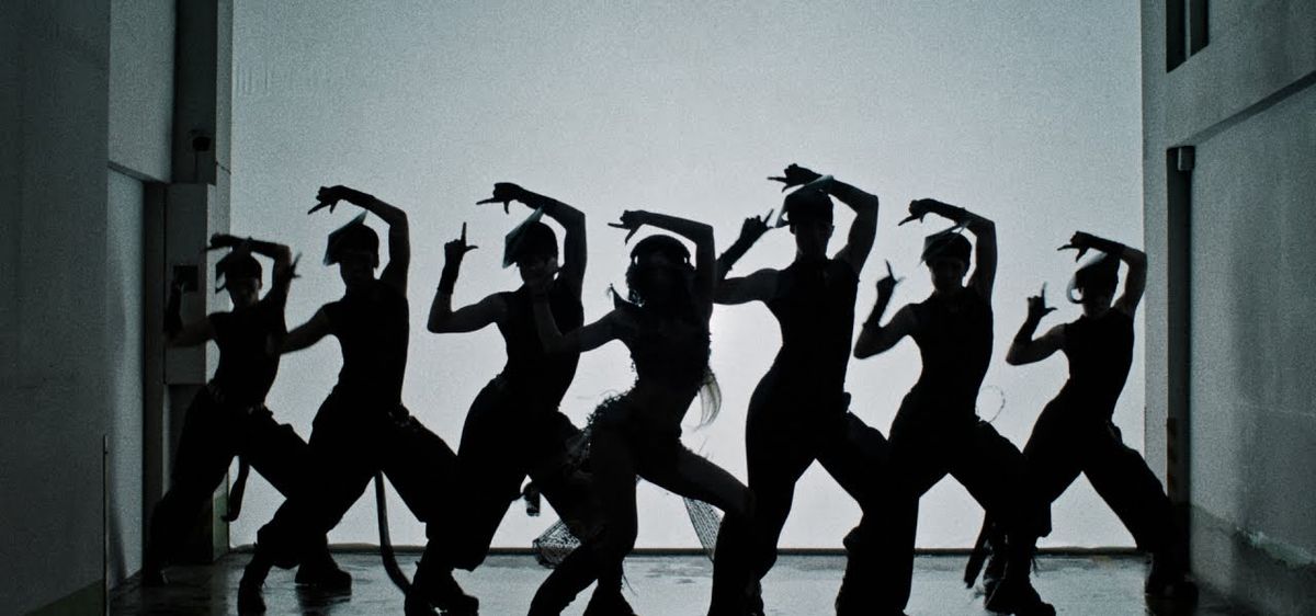 Fotograma de archivo del video de «SaWaDiKa»: siluetas negras de LISA y su cuerpo de baile haciendo la misma coreografía, con los brazos en alto, contra una pared blanca iluminada