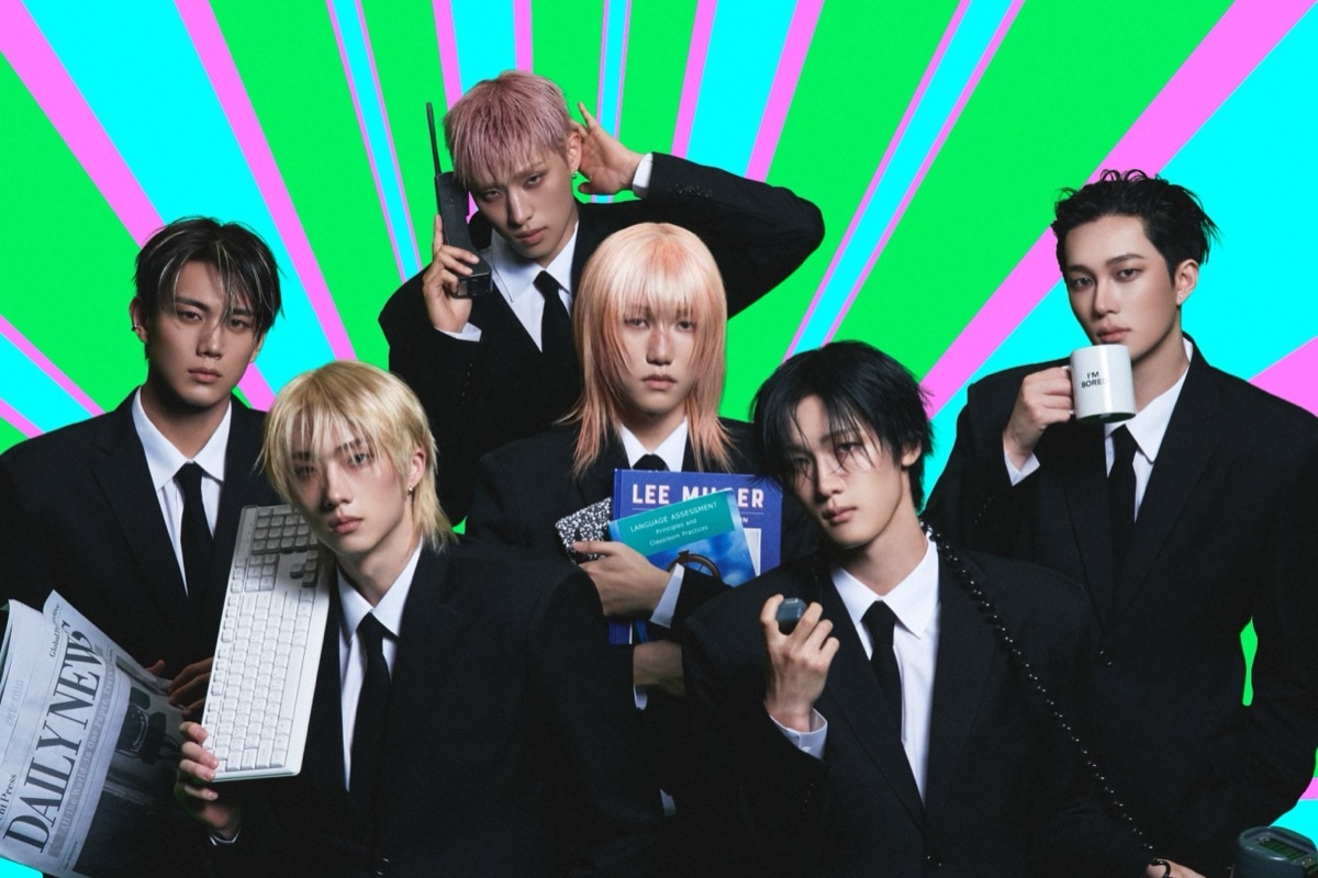 Foto conceptual oficial de P1Harmony para «BLOW UP»: los seis integrantes de traje negro y corbata posan con un teclado, un diario, un teléfono, un libro y una taza frente a un fondo de rayos verdes, celestes y rosas