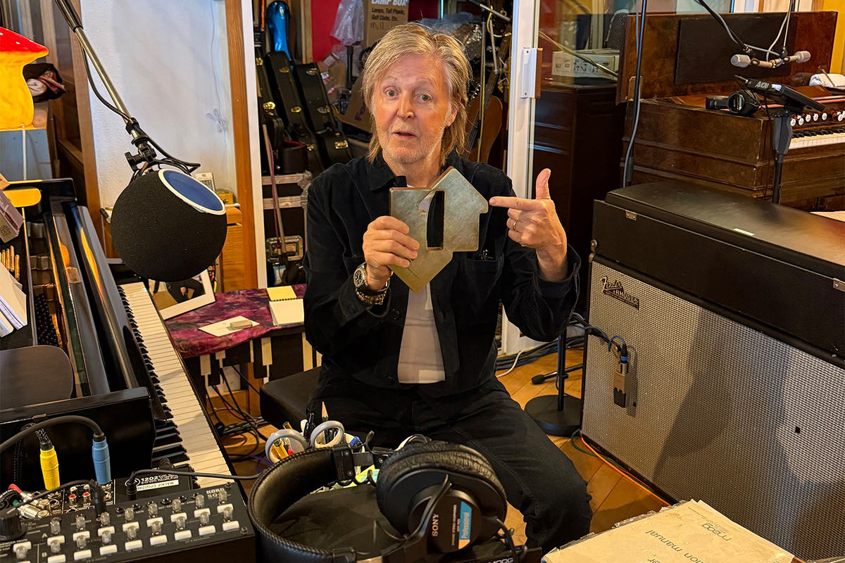 Paul McCartney en su estudio, sentado entre un piano, un micrófono y un amplificador, muestra el trofeo por el primer puesto de