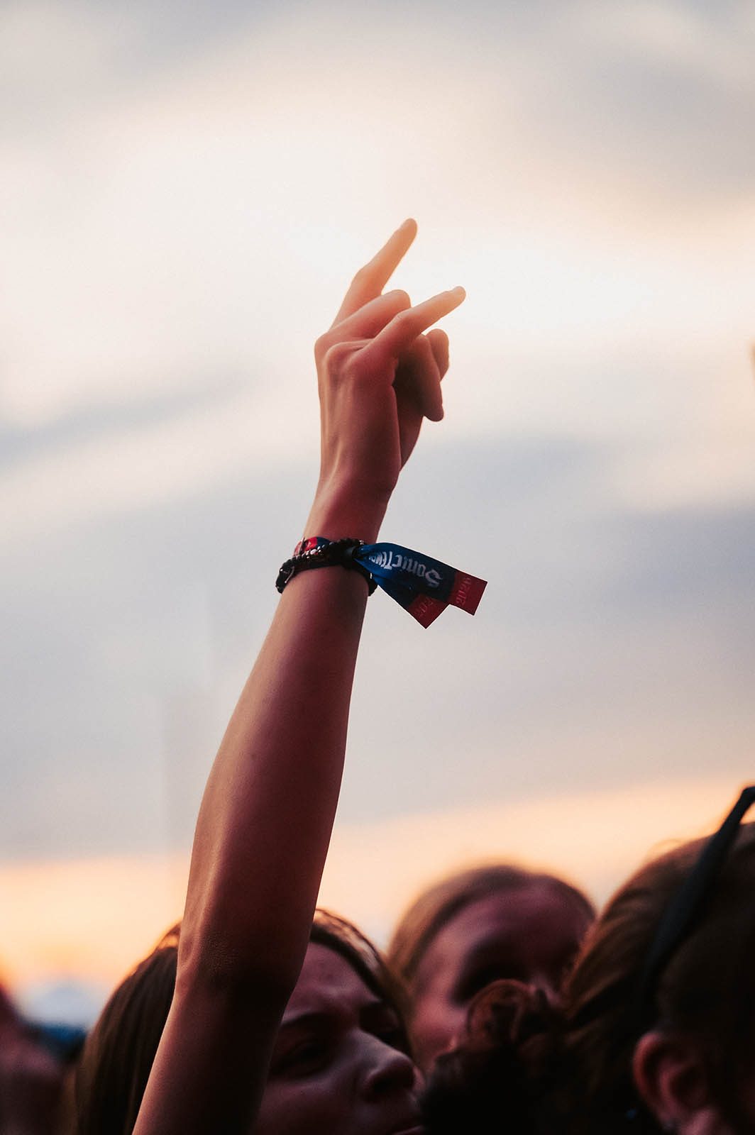Una fan levanta la mano con la pulsera de tela de Sonic Temple en la muñeca, contra un cielo de atardecer, en la edición 2026 del festival (foto de archivo). Foto: Sonic Temple