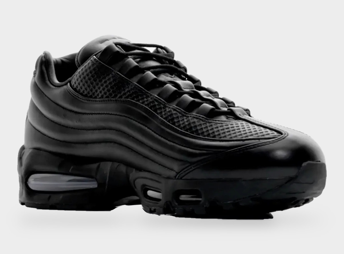 Nike Air Max 95 Lux de One Block Down de perfil sobre fondo gris claro, con cuero negro en las capas laterales, la zona de la puntera con textura cuadriculada y la cámara Air visible en el antepié y el talón