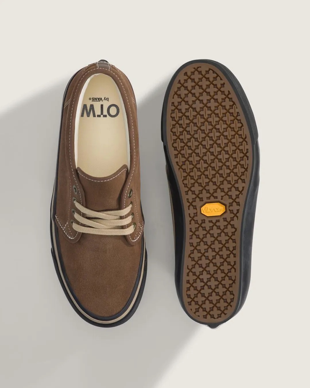 Vista desde arriba de la OTW by Vans Chukka 49 Vibram Vintage Cocoa junto a otra dada vuelta: a la izquierda la gamuza marrón con cordones beige y la plantilla con el logo OTW by Vans, a la derecha la suela con dibujo geométrico y el logo amarillo de Vibram