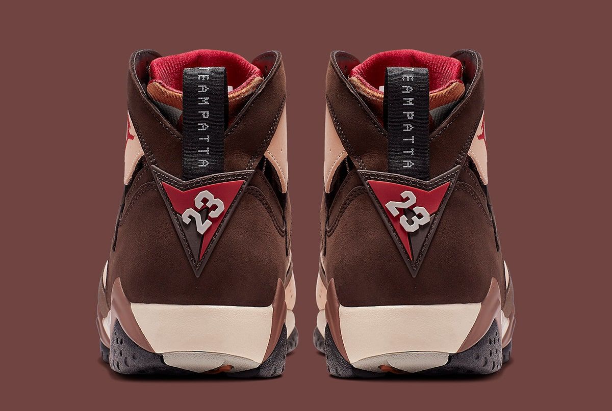 Foto de archivo: vista trasera del par de Patta x Air Jordan 7 Shimmer de 2019, con el tirador negro que dice TEAMPATTA, el triángulo rojo con el número 23 y la suela en tonos crema y gris