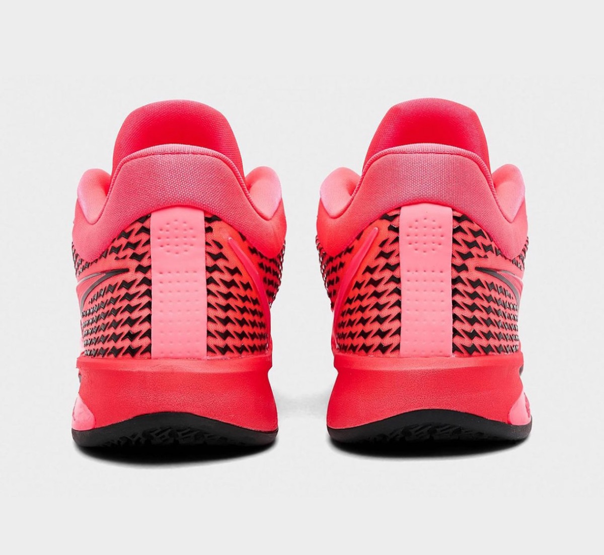 Vista trasera del par Nike Sabrina 4 Light Work, con la pieza rosa perforada del talón y la malla roja con el dibujo negro repetido alrededor del contrafuerte