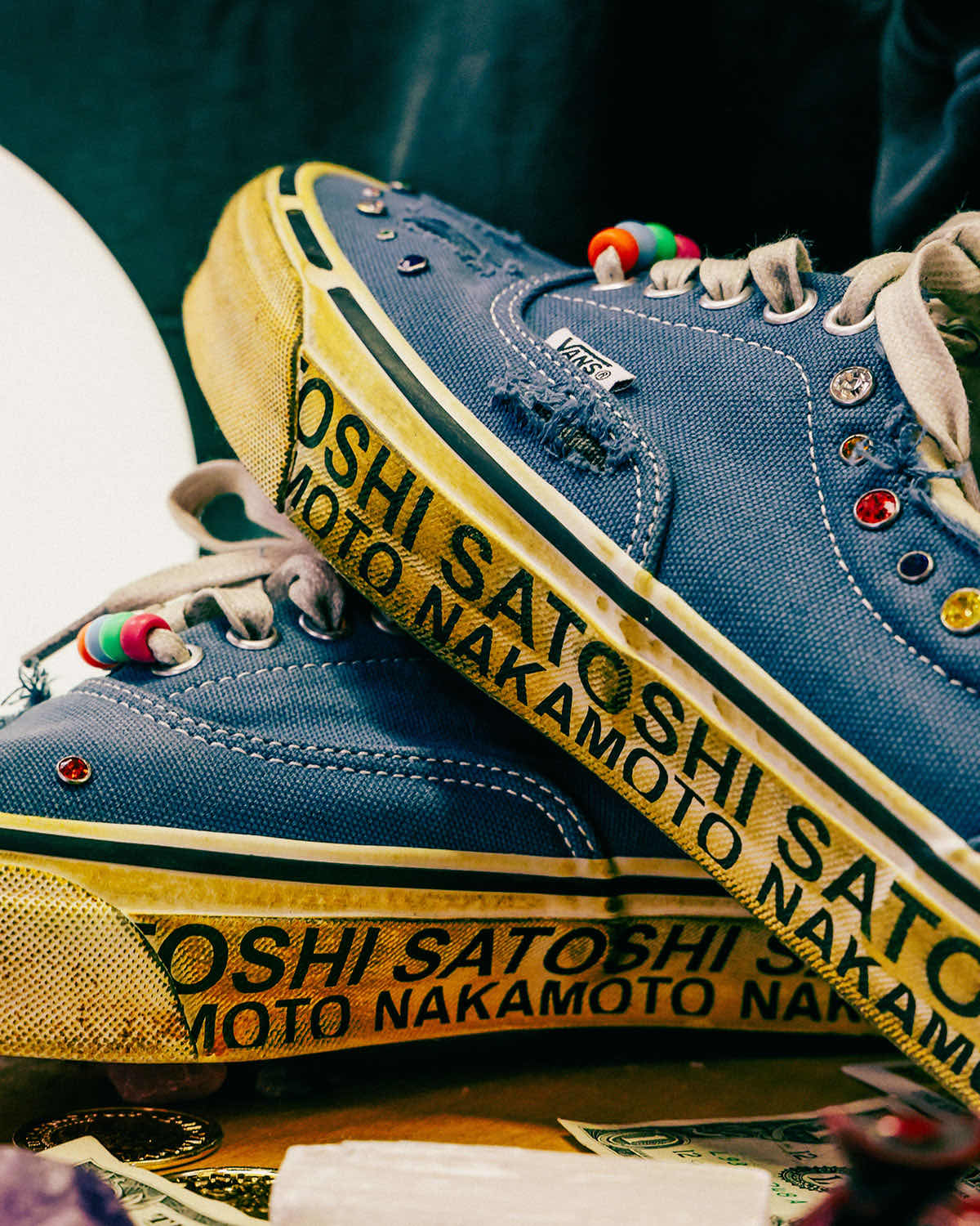Detalle de la mediasuela envejecida del Satoshi Nakamoto x Vans Era con el texto SATOSHI NAKAMOTO repetido, joyas en el upper azul y cuentas en los cordones