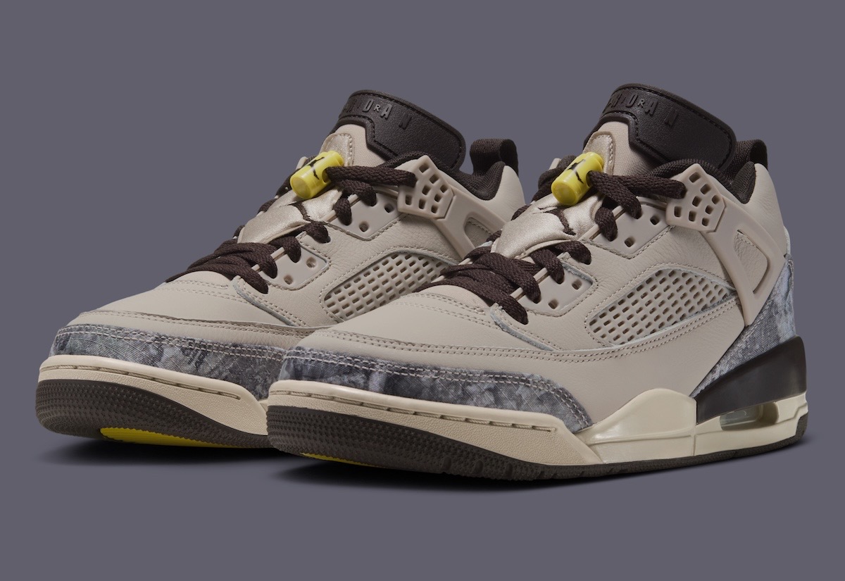 Par del Jordan Spizike Low Realtree Camo en tres cuartos sobre fondo gris, con upper crema, camuflaje gris en la punta, cordones marrón oscuro, traba de cordones amarilla y una burbuja de aire visible en el talón