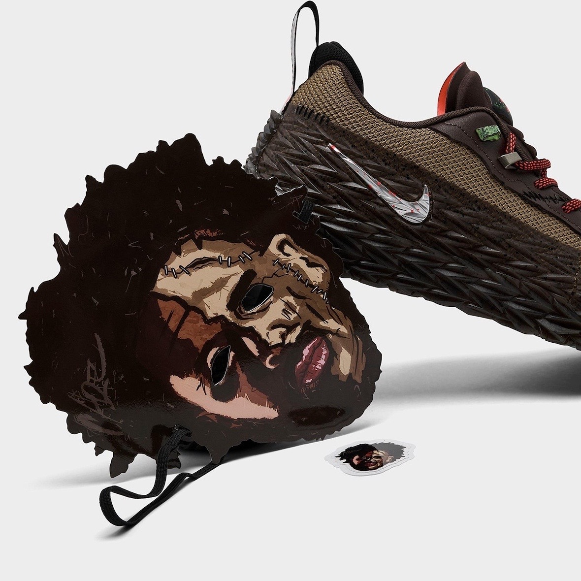 Nike ST Charge Halloween de Cade Cunningham de costado junto a la máscara ilustrada que lo acompaña, con la cara de Cade convertida en Leatherface, piel cosida con puntadas y elástico negro, y un sticker chico con la misma imagen, sobre fondo blanco