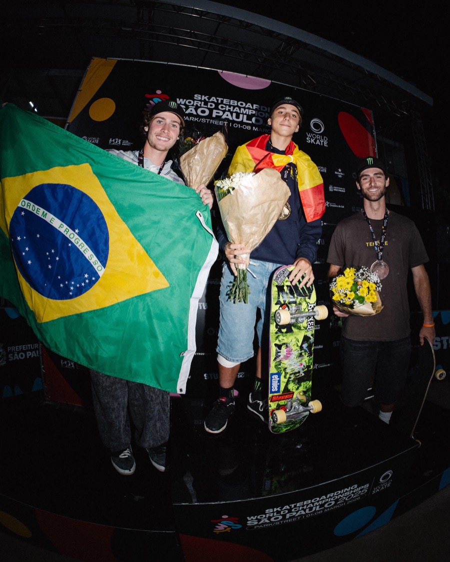 Egoitz Bijueska, con la bandera de España sobre los hombros, sostiene su tabla y un ramo de flores en lo más alto del podio del Mundial de San Pablo, con Kalani Konig y la bandera de Brasil a su lado