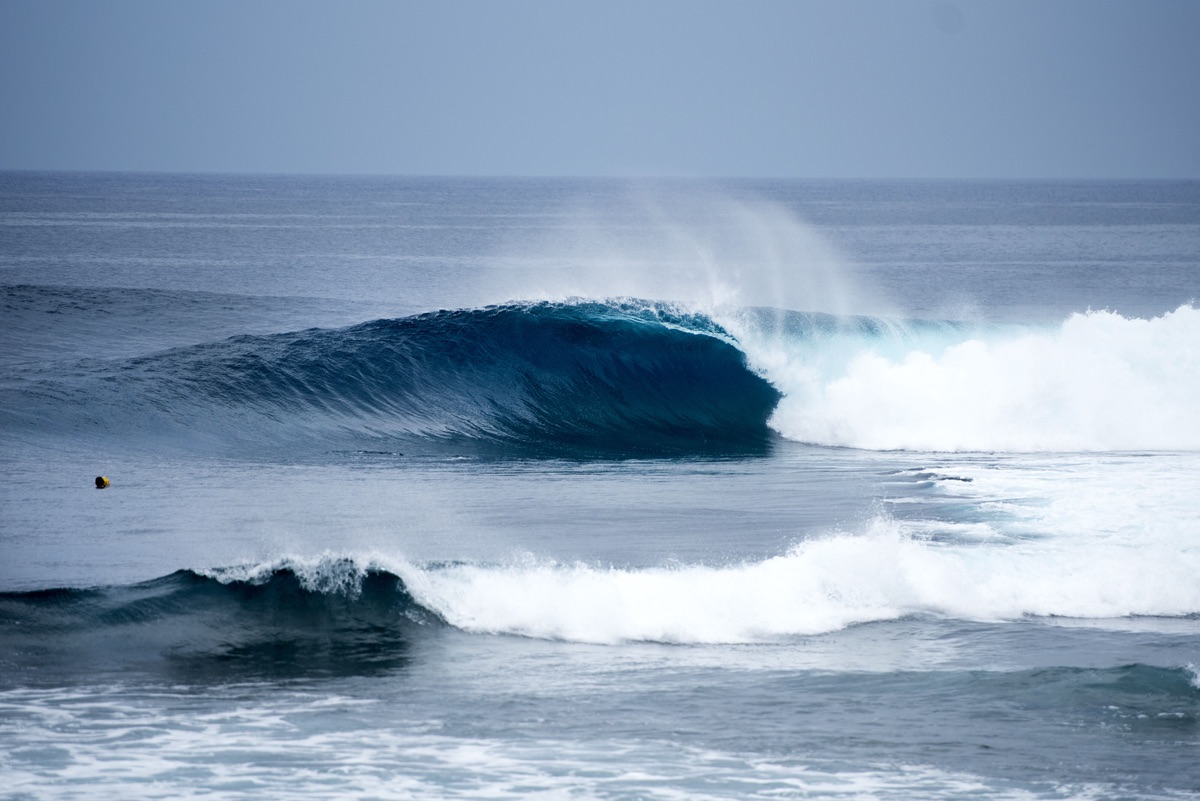 Una ola derecha y tubular rompe sobre el arrecife de Cloud 9, en Siargao, con el mar azul de fondo y espuma blanca en primer plano