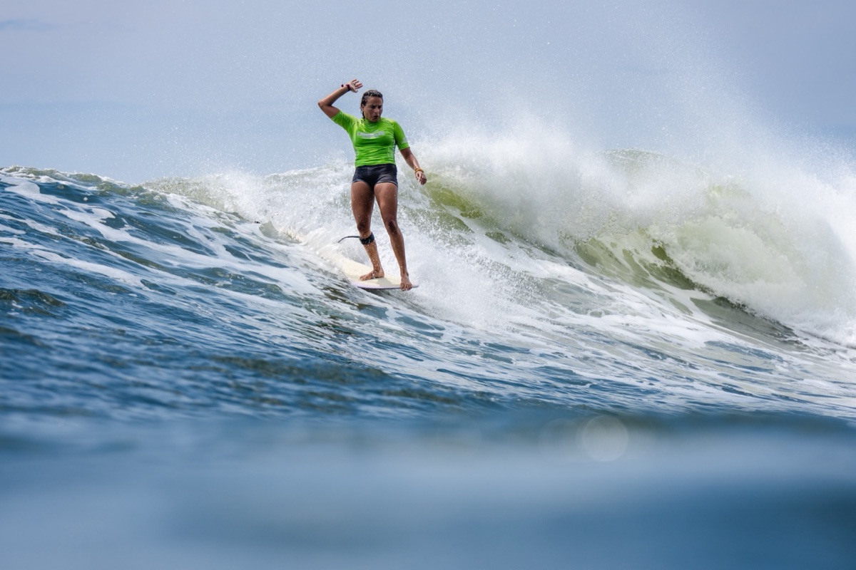 Alice Lemoigne, con lycra verde, camina sobre su longboard con un brazo en alto en una ola de El Sunzal, en la quinta jornada del Mundial, el miércoles 21
