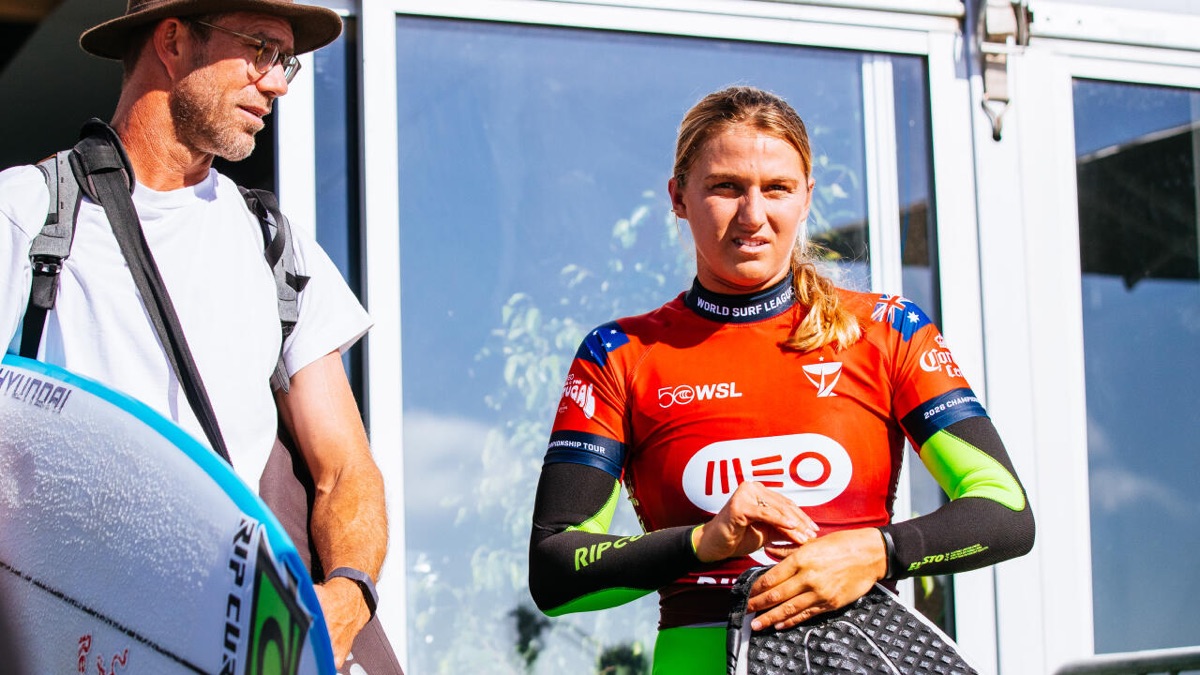 Molly Picklum, con la lycra roja del MEO Rip Curl Pro Portugal y la bandera de Australia en las mangas, escucha a su entrenador junto a la zona de competidores en Supertubos