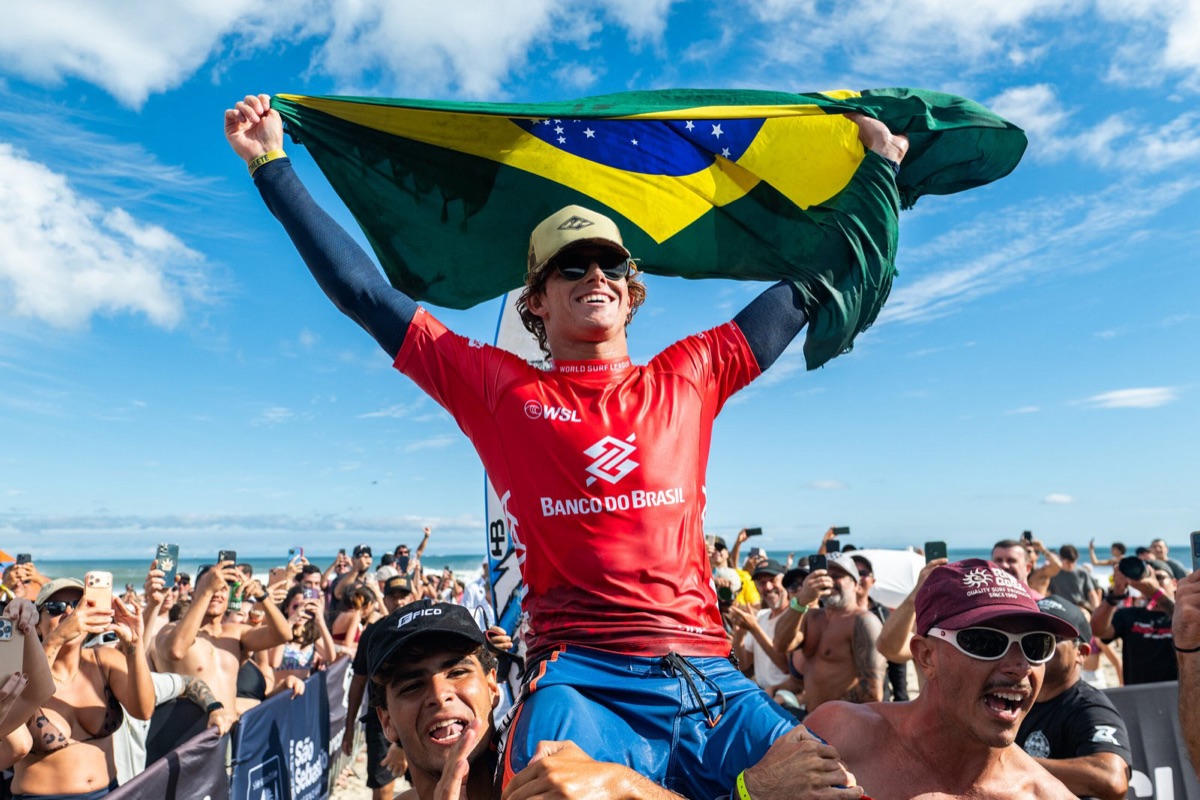 Ryan Kainalo, con la lycra roja de Banco do Brasil, levanta la bandera de Brasil en andas de la gente en la playa de Maresias