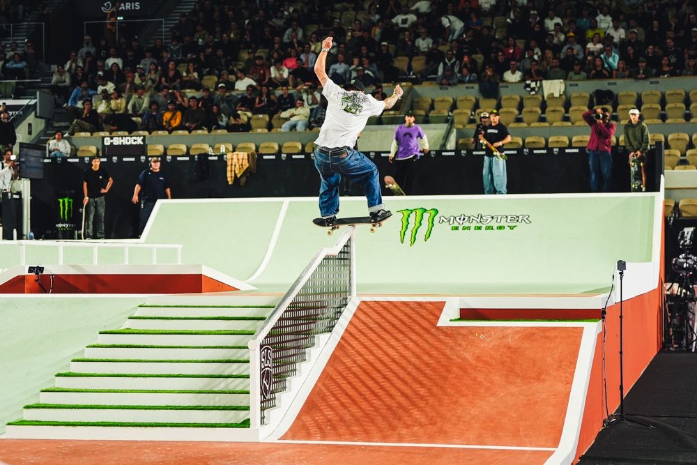 Giovanni Vianna, de remera blanca y jean, sube con la tabla en boardslide por la baranda de la escalera, frente a la tribuna de Roland-Garros